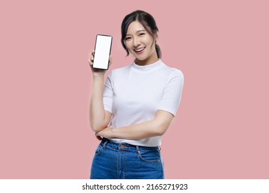 Happy Young Asian Woman Feeling Happiness And Gesture Showing Mobile Smartphone Blank Screen On Isolated Pink Background.