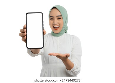 Happy young Asian woman in green hijab and white blouse presenting smartphone blank screen with open hand gesture isolated on white background - Powered by Shutterstock