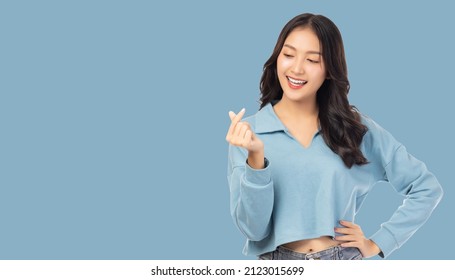 Happy young asian woman holding something and looking at her holding with happy Standing over pastel blue background copy space Holding copy space imaginary on beauty palm for insert advertisement