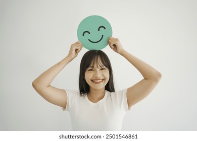 Happy young Asian woman holding smile emoji face, positive mental health, world mental health day concept
 - Powered by Shutterstock