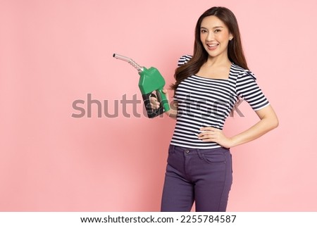 Happy young Asian woman holding oil dispenser isolated on pink background, Gasoline and refueling car concept