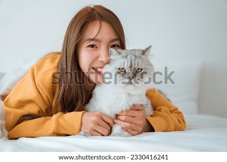 Happy young asian woman hugging cat on bed at home, Good friends. Friendship of a pet and its owner. Adorable domestic pet concept.