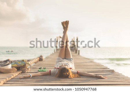Happy young asian woman is lift and cross her leg on wooden bridge pier near the beach during sunset background. - Vintage style and lifestyle for travel concept.
