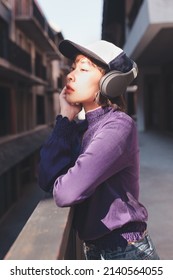 Happy Young Asian Woman Listening To Music With Headphones On The Street.