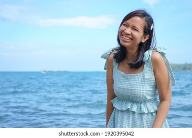 Happy Young Asian Woman On Tropical Beach Summer Vacation, Wearing Blue Dress. Close Up Of Pretty Girl Smiling Outdoors. Lifestyle And Holiday Concept.