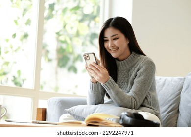 Happy young asian woman relax on comfortable couch at home texting messaging on tablet, smiling girl use tablet, chatting online message, shopping online from home - Powered by Shutterstock