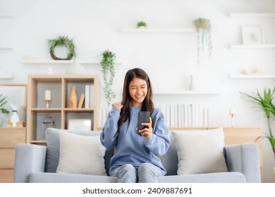 Happy young asian woman relax on comfortable couch at home texting messaging on smartphone, smiling girl use cellphone, chatting online message, shopping online from home - Powered by Shutterstock