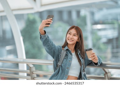 Happy young asian woman taking selfie photo on mobile phone at city, female using smartphone camera for self portrait outside. - Powered by Shutterstock