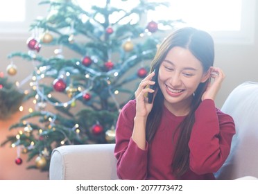 Happy Young Asian Woman Talking On Phone With Friend During Christmas Season.