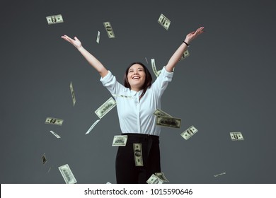 happy young asian woman throwing dollar banknotes isolated on grey