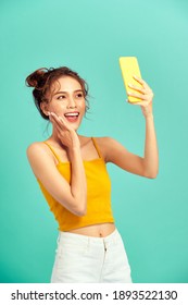 Happy Young Asian Woman Using Phone Over Light Green Background.