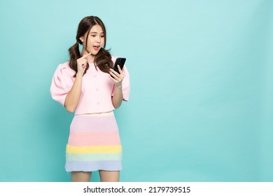 Happy young Asian woman using mobile phone or touching screen application on smartphone isolated on green background