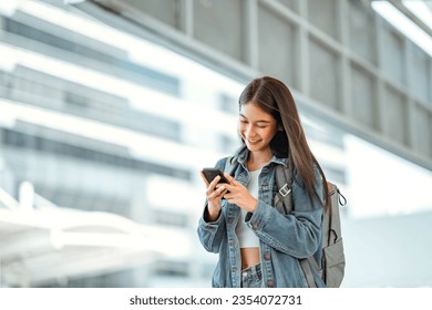 Happy young asian woman using social media on mobile phone in a urban city. Smiling female checking message on mobile phone in town. - Powered by Shutterstock