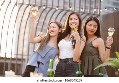 Happy young Asian women gang drinking champagne while enjoying rooftop bar party. Girls best friends having fun at terrace party. Concept about women night out.