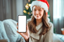 Happy Young Asian Women Wearing Santa Hat And Show Smartphone Mock Up With Blank Screen In Christmas Time. Put Your Text In Empty Space.