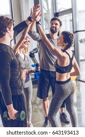 Happy Young Athletic People In Sportswear Giving High Five In Gym