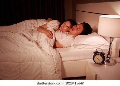happy young attractive couple hugging and sleeping on bed at night