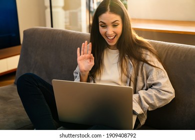 Happy Young Attractive Woman Looking At Laptop Screen, Waving Hands, On A Video Call With Friends From Home