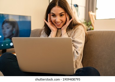 Happy Young Attractive Woman Looking At Laptop Screen, Waving Hands, On A Video Call With Friends From Home