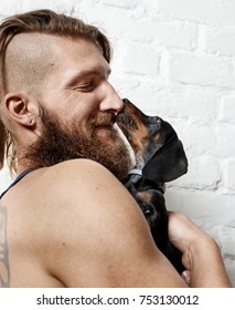 Happy young bearded man holding little dachshund puppy. - Shutterstock ID 753130012