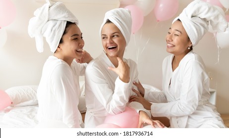 Happy Young Beautiful Caucasian Bride Preparing For Wedding Day With Excited Asian Bridesmaids, Enjoying Fun Time After Spa Procedures Together In Luxury Hotel, Wearing Towels On Heads And Bathrobes.