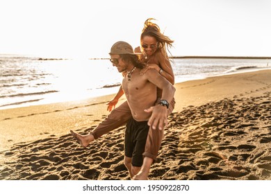 Happy young beautiful couple having fun on the beach during sunset, hugging and smiling. Summer vibes. Real people emotions and lifestyle.