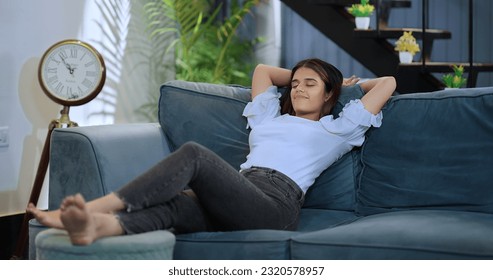 Happy young beautiful smiling woman sitting resting  on sofa raising arms stretching back muscles enjoying peaceful weekend at home. Indian female leaning on couch with closed eyes  hands behind head - Powered by Shutterstock