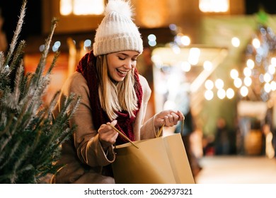 Happy young beautiful woman choosing christmas present and tree at market