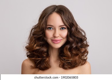 Happy young beautiful woman with curly hair. grey background