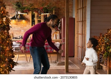 Happy Young Biracial Father And Small Son Listen To Music Dance Together Near Christmas Tree At Home. Overjoyed African American Dad And Little Boy Child Have Fun Enjoy New Year Winter Holidays.