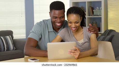 Happy Young Black Couple Using Tablet Computer Together Laughing