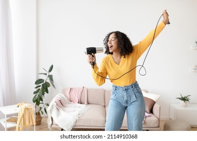 Happy Young Black Lady With Hair Dryer As Microphone Singing And Dancing At Home, Copy Space. Beautiful African American Woman Pretending To Be Rockstar, Having Fun Indoors