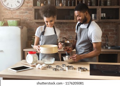 Happy young black woman and man baking pie in loft kitchen - Powered by Shutterstock