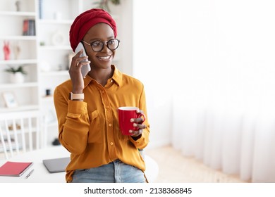 Happy Young Black Woman With Red Headscarf Talking On Phone With Lover Or Girlfriend While Having Coffee Break At Office, Holding Red Mug, Looking At Copy Space And Smiling, Panorama