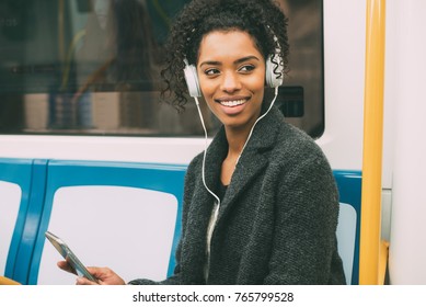 Happy Young Black Woman Sitting Inside The Underground Listening To Music