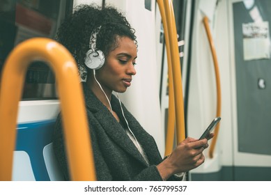 Happy Young Black Woman Sitting Inside The Underground Listening To Music