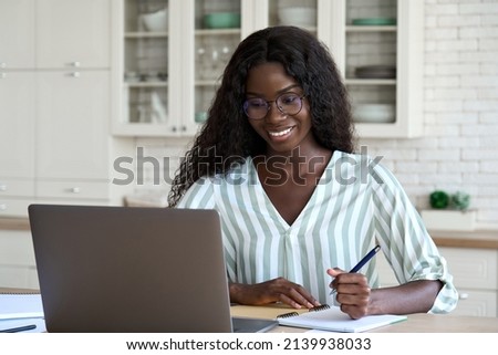 Happy young black woman student learning at home looking at laptop computer watching online webinar, having virtual work meeting or elearning training seminar class on video call digital conference.
