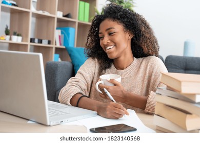 Happy young black woman studying at home