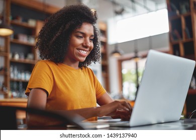 Happy Young Black Woman Using Laptop In Cafe