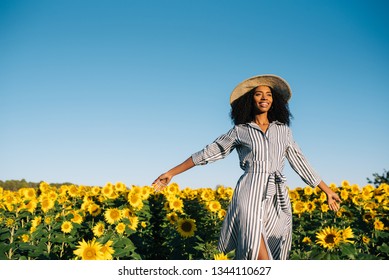 Happy Young Black Woman Walking In A Sunflower Field