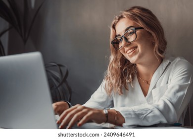 Happy young blonde business woman entrepreneur using computer looking at screen working in internet sit at office desk, smiling millennial female professional employee typing email laptop at workplace - Powered by Shutterstock