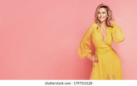 Happy young blonde woman in maxi yellow dress , posing on pink pastel studio background. - Powered by Shutterstock