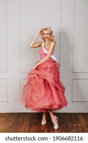 Happy Young Blonde Woman Wearing A Crown, Pink Dress And A White Ribbon, Smiling. Beauty Contest Winner Concept.