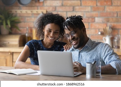 Happy Young Bonding African American Family Couple Looking At Computer Screen, Reading Email With Good News, Enjoying Web Surfing Information Online, Communicating Distantly, Using Modern Tech Gadget.