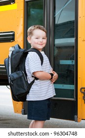 Happy Young Boy In Front Of School Bus Going Back To School