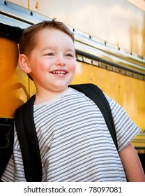 Happy Young Boy In Front Of Yellow School Bus Waiting To Board On First Day Back To School.