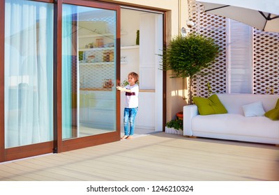 happy young boy, kid opening the sliding door on rooftop patio area at home
