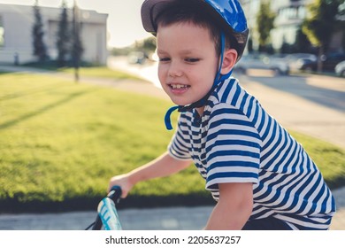 Happy Young Boy Riding His Bike. A Cute Elementary Age Boy Dressed In A Casual Clothing, Going To Ride The Bicycle On A Sidewalk In A City.