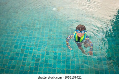 Happy young boy swim and dive underwater, kid breast stroke with fun in pool. Active healthy lifestyle, water sport activity and lessons with parents on summer family vacation with child. - Shutterstock ID 1956159421