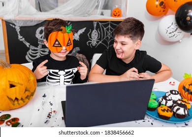 Happy young boys, brothers talking with grandparents via video call using laptop on halloween day , excited kis showing his new mask for halloween on camera